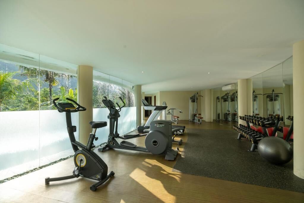 A gym with cardio machines, weightlifting equipment, and a large mirror.