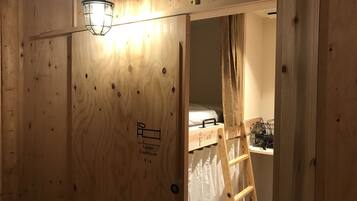 A wooden room with a ladder, a bed, and a light fixture.