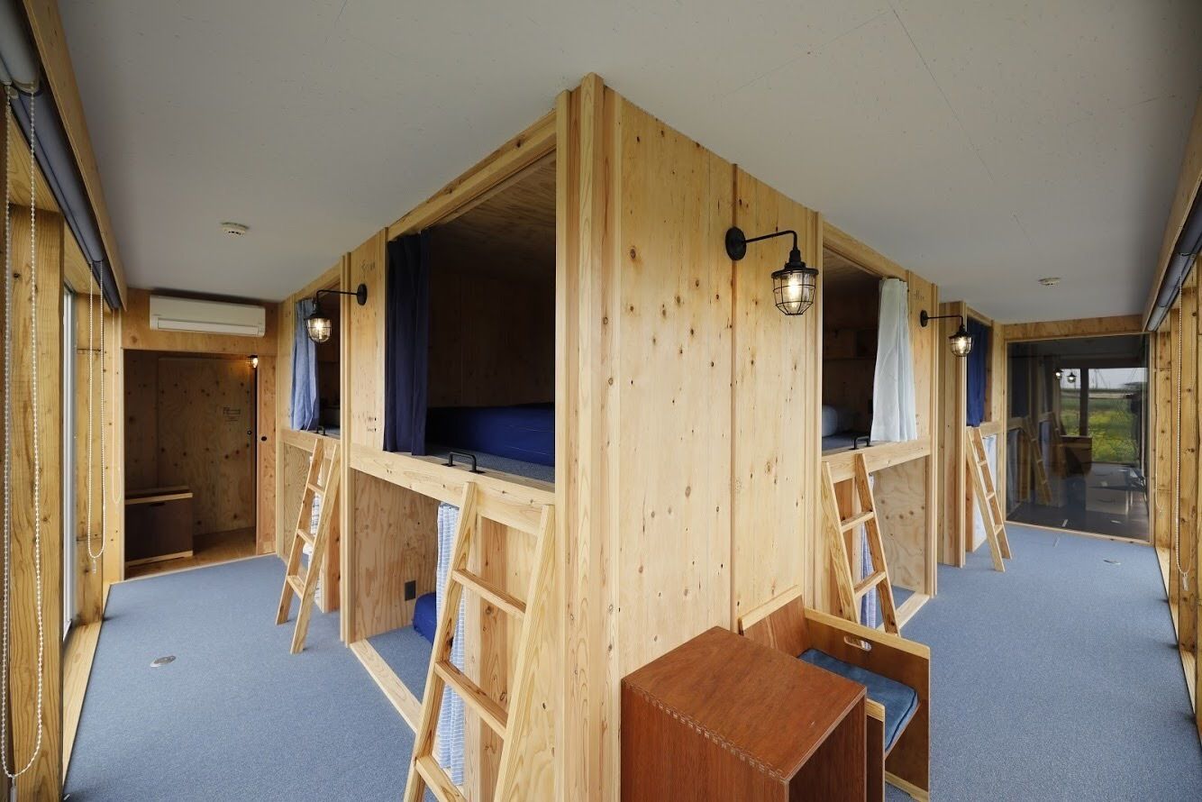 A wooden cabin with bunk beds, a ladder, and a small table.
