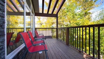 Relax on the deck with a view of the surrounding trees, surrounded by comfortable chairs.