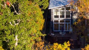 Una casa circondata da fitta vegetazione, con vista aperta sul paesaggio e sullo specchio d'acqua circostanti.