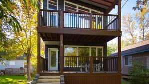 Una casa in legno a due piani con un balcone, un braciere e un vialetto lastricato.