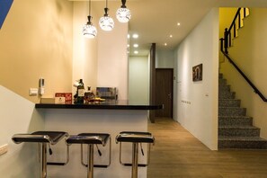 A kitchen with a bar area, a staircase, and a door leading to another room.
