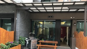 Un patio al aire libre con una parrilla, un banco de madera y piso de baldosas.