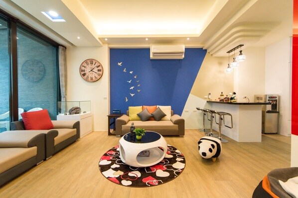 A modern living room with a sofa, a round coffee table, and a decorative wall with a clock and a wall art of birds.
