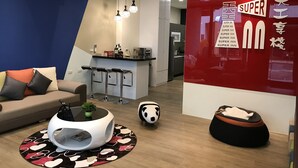 Una sala de estar moderna con un sofá, una mesa redonda de centro y un reposapiés con forma de panda. Cuenta con una zona de cocina con barra y lámparas colgantes.