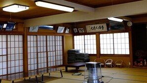 Una habitación japonesa tradicional con suelo de tatami, una mesa baja, un calentador y puertas correderas.
