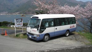 Un autobús estacionado cerca de un lago pintoresco con montañas al fondo.