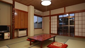 Una habitación con tatami, una mesa baja, televisor y puerta corredera.