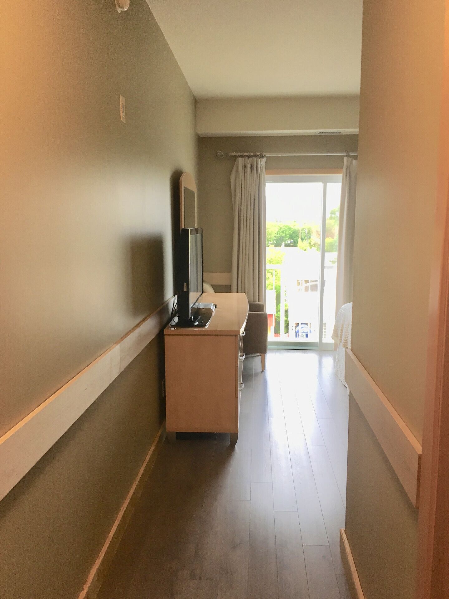 Un pasillo de hotel con una recepción, un televisor y vistas al exterior a través de un ventanal.