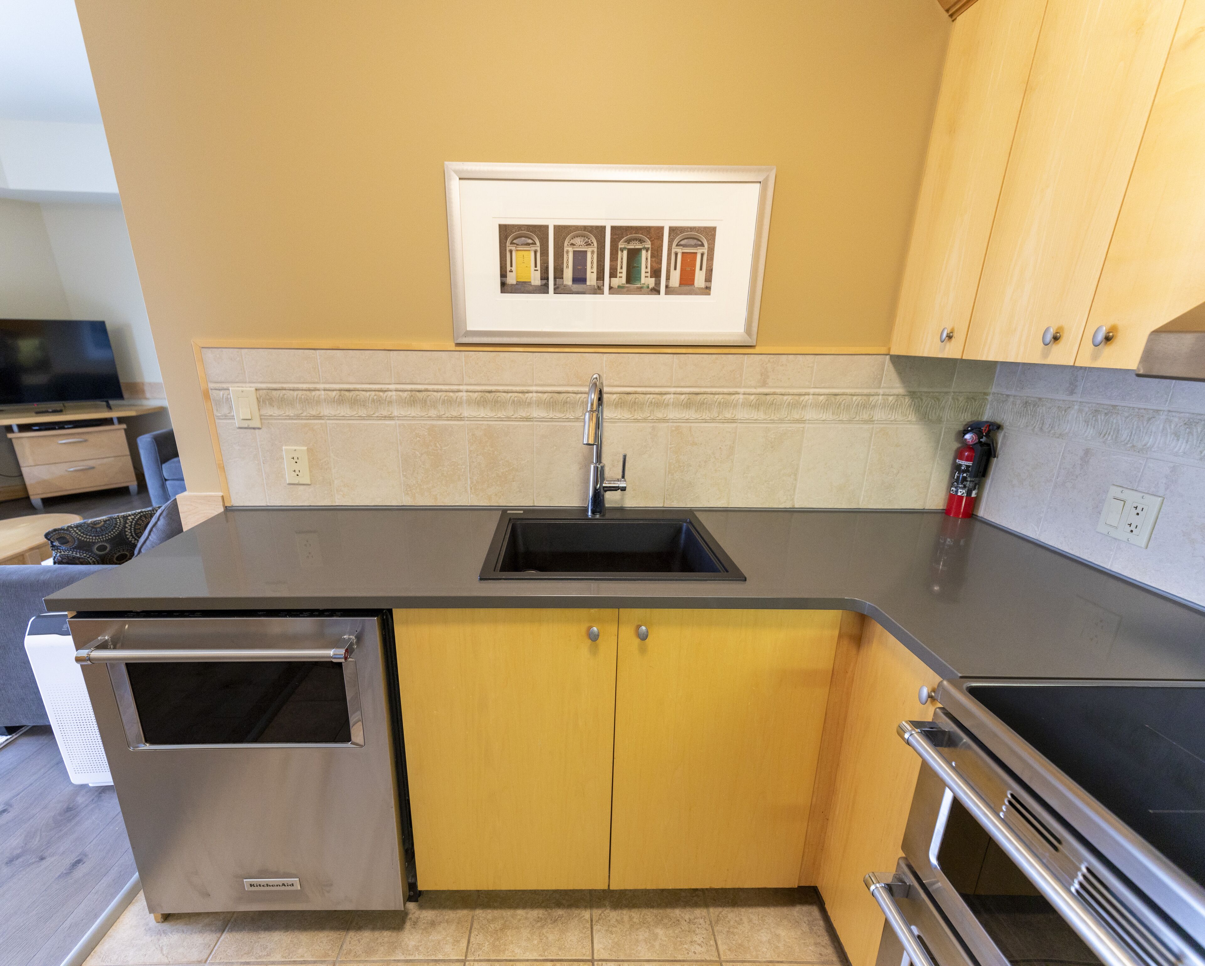 A modern kitchen with stainless steel appliances, a built-in sink, and yellow cabinetry.