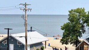 Una playa con gente nadando y jugando, un poste de electricidad y un edificio con un letrero que dice "JET SKI".