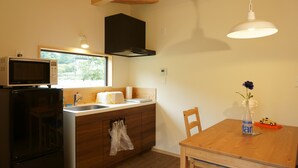 Une cuisine de taille réduite, équipée d’un four à micro-ondes, d’un évier et de meubles de rangement en bois.