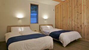 Une chambre avec deux lits, des murs en bois, une fenêtre avec des stores et des lampes fixées au mur.