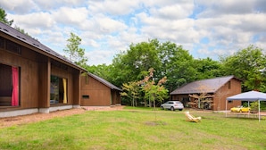 Un grand jardin à l’arrière de la maison, avec une pelouse, une construction en bois et une voiture garée à proximité.