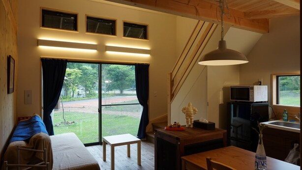 Une pièce confortable avec un lit, une petite table, un banc en bois et une fenêtre avec des rideaux.