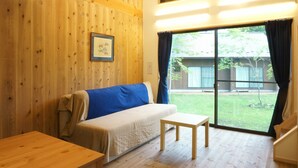 Une petite pièce chaleureuse aux murs en bois, avec un lit simple, une petite table et une fenêtre avec des rideaux.