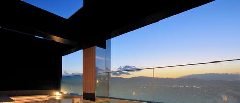 Ein moderner Pool im Freien mit Glasbarriere, Blick auf den Himmel und eine entfernte Landschaft.
