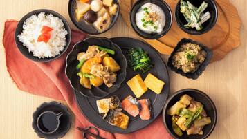 A variety of Japanese dishes including rice, fish, and vegetables, served on black plates and bowls.