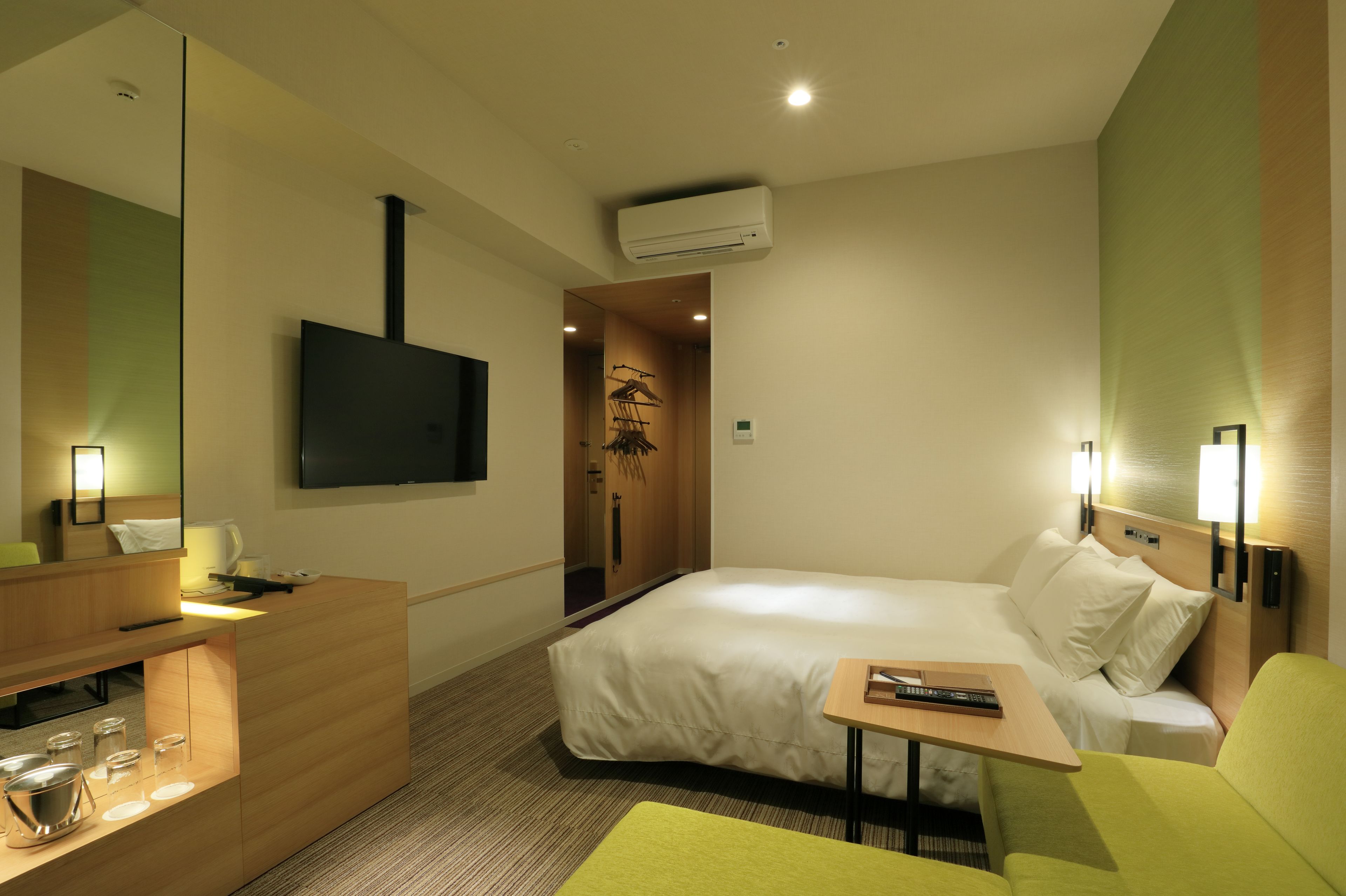 A hotel room with a bed, a desk, a TV, and a mirror.