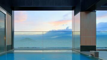 Una piscina infinita moderna con vistas claras al océano y un atardecer.