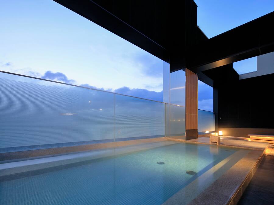 A modern outdoor pool with glass railings, a clear view of the sky, and a minimalist architectural design.