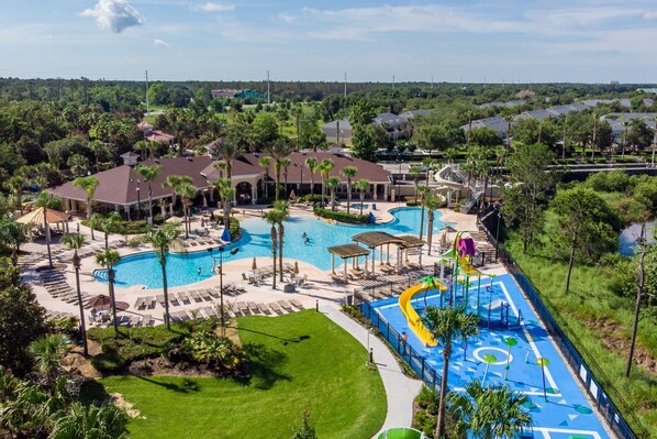 A resort with a large swimming pool, sun loungers, and a water slide.