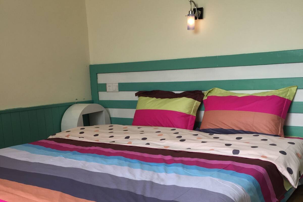 A bed with a colorful striped bedspread and a headboard with horizontal stripes.