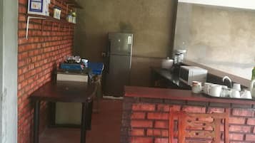 A compact kitchen with a refrigerator, a sink, and a blue table.