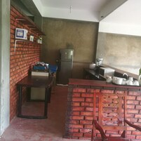 Una cocina compacta con refrigerador, un lavamanos y una mesa azul.