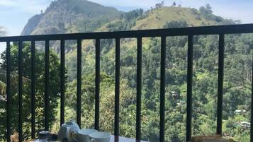 Un balcón con una mesa dispuesta para el desayuno, con vistas a un paisaje montañoso.