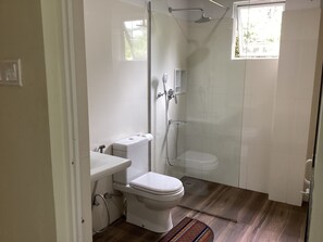 A bathroom with a toilet, a shower, and a window. - Viewfront Ella (Ella)
