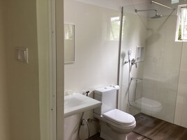 Un baño moderno con cabina de ducha de vidrio, inodoro blanco y lavamanos.