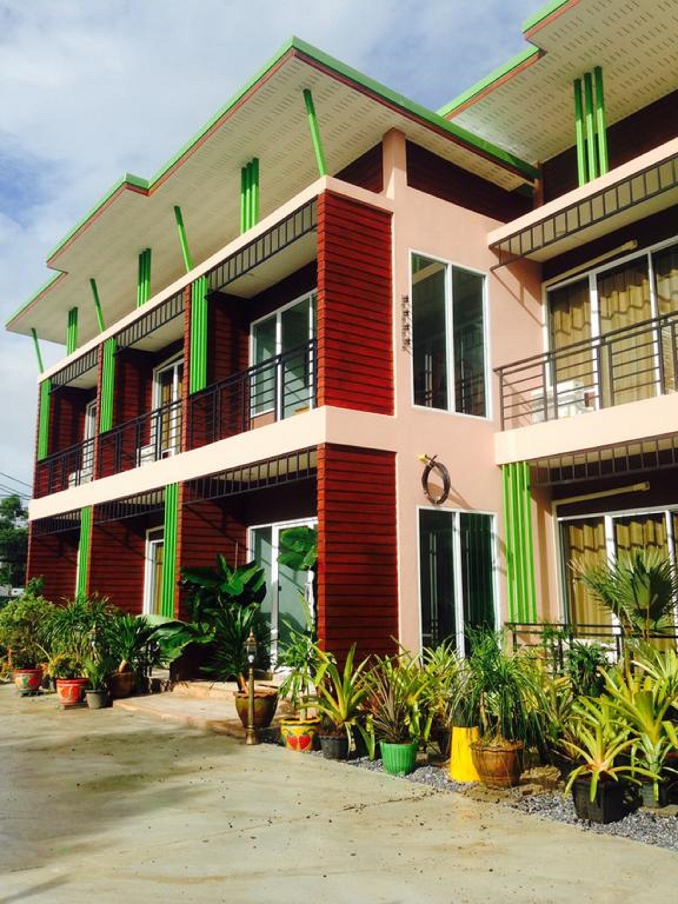 A multi-story building with balconies, large windows, and potted plants in the foreground.