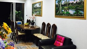 A dining area with a table, chairs, and a sofa. There are two framed paintings on the wall. - Baan Suan Punpaka Resort (La-ngu)