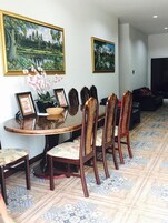 Un comedor con una mesa redonda, seis sillas y dos cuadros enmarcados en la pared.