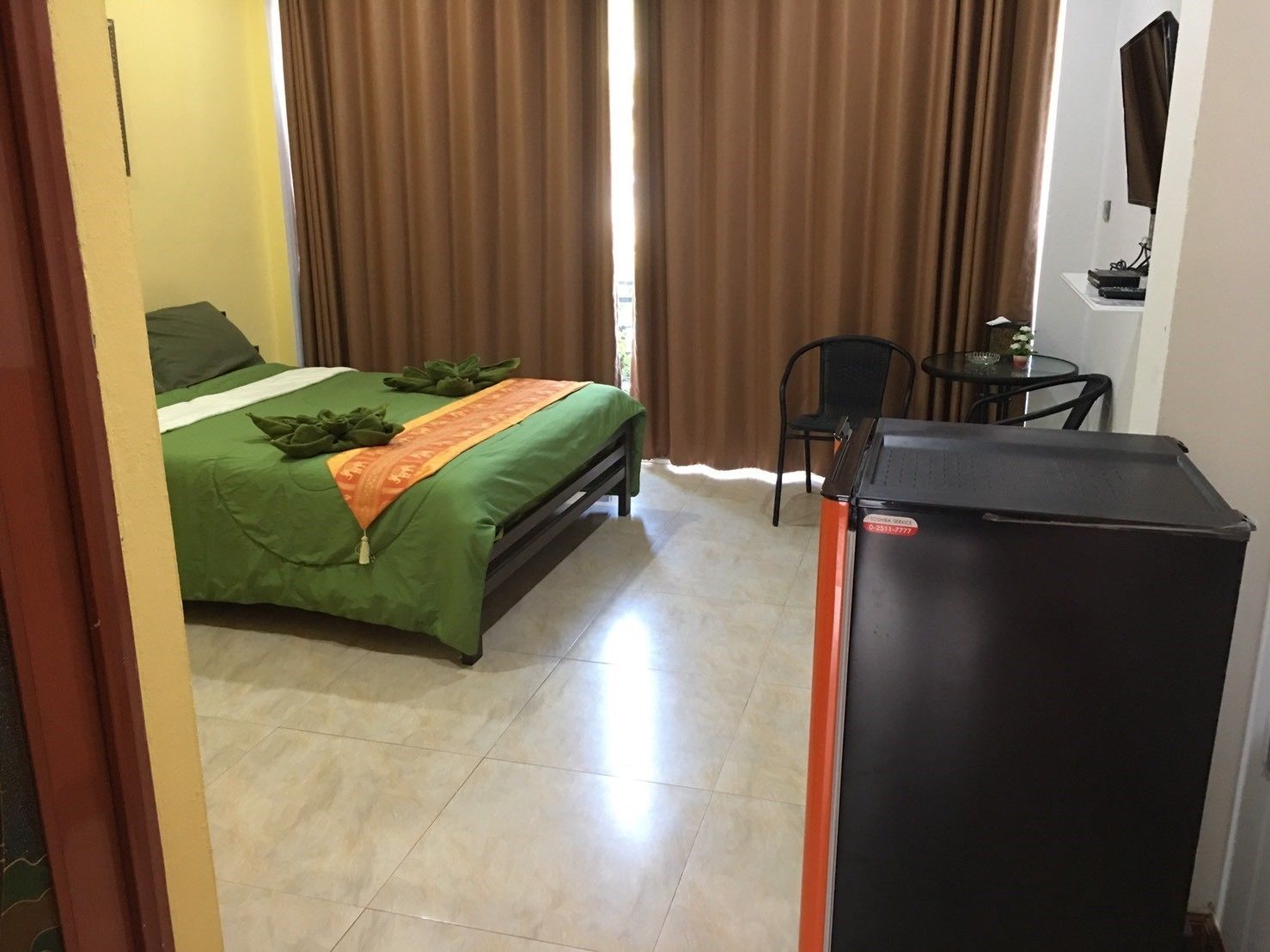 Une chambre d’hôtel avec un lit, un bureau et un réfrigérateur.