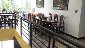 A dining area with tables and chairs, a staircase, and a view of greenery outside. - Baan Suan Punpaka Resort (La-ngu)