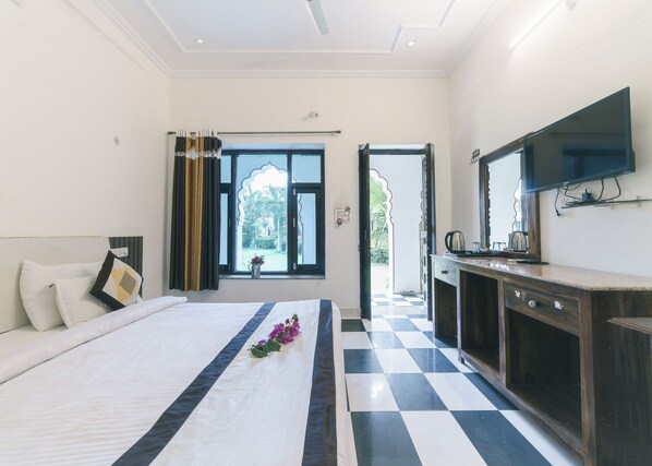 Una habitación de hotel con cama, mesita de noche, espejo, ventana con cortinas y suelo a cuadros.