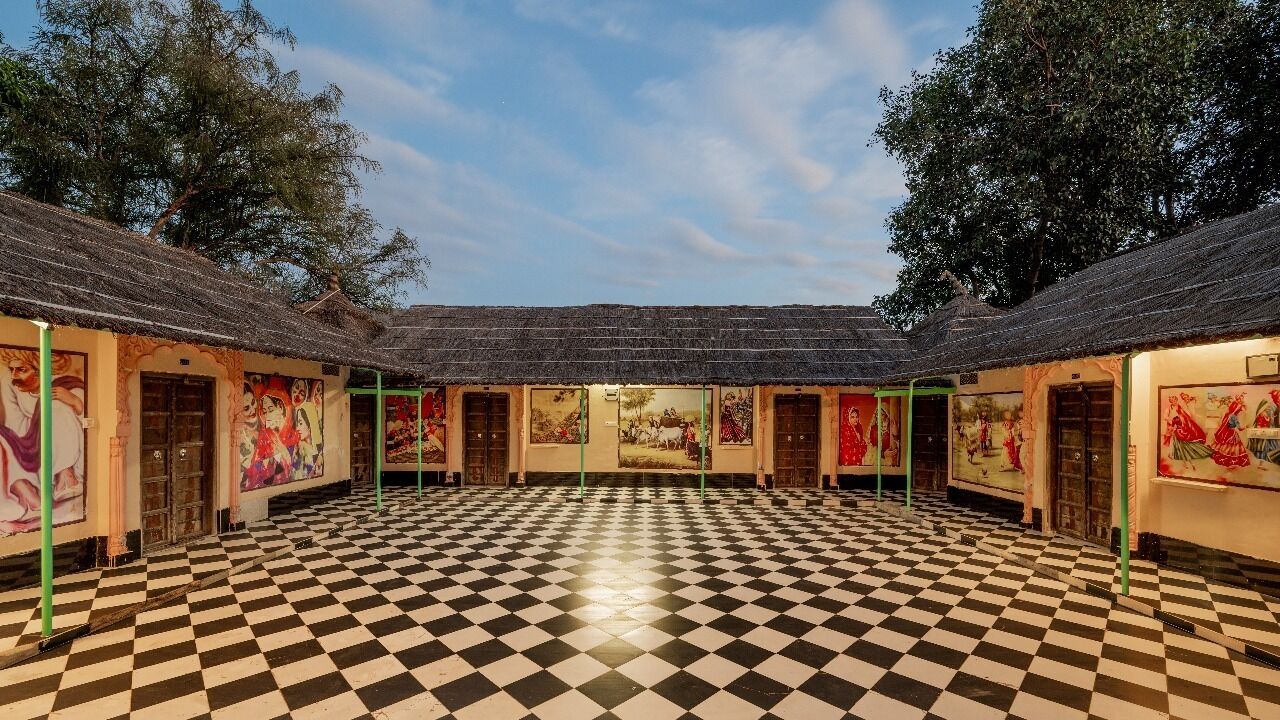 A spacious room with a checkered floor, multiple doors, and walls adorned with colorful artwork.