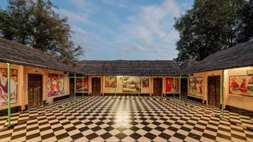 A spacious room with a checkered floor, multiple doors, and walls adorned with colorful artwork.