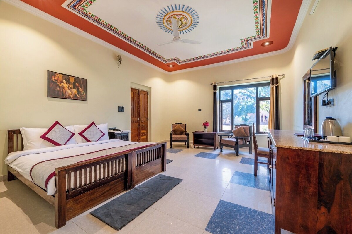 Une chambre d’hôtel équipée d’un lit, d’un bureau, d’une chaise, d’une fenêtre et d’un ventilateur de plafond.