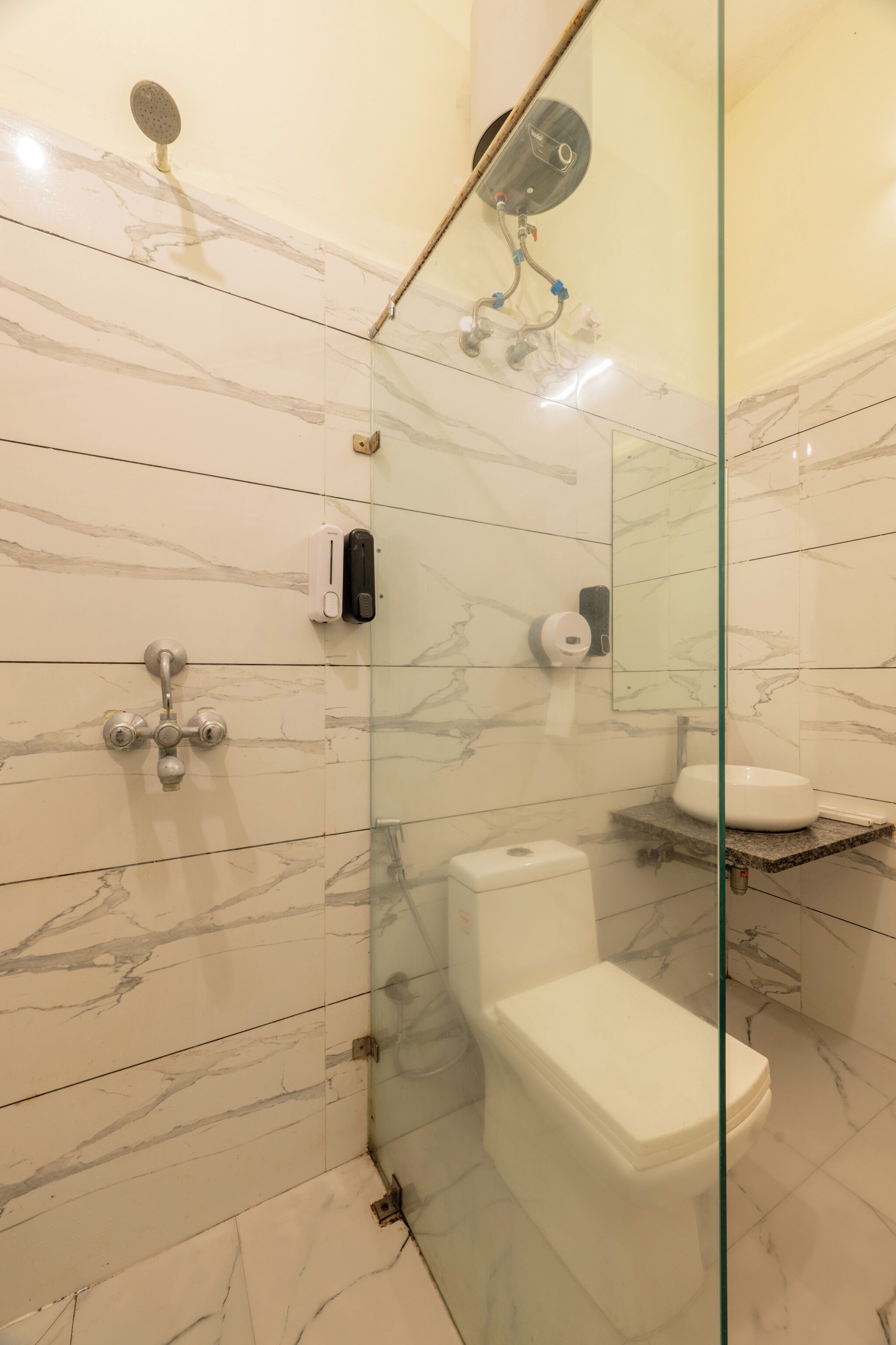 A modern bathroom with a glass-enclosed shower, a toilet, and a sink.