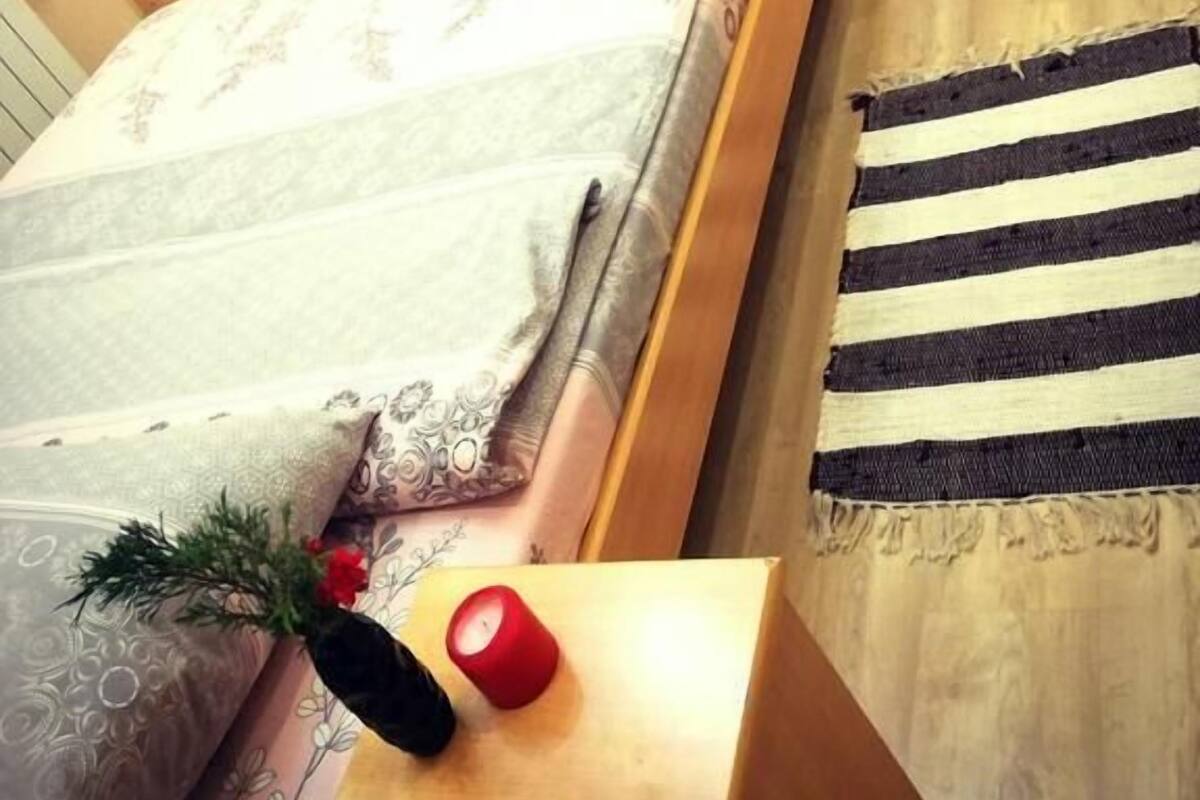 A bedroom with a bed, a television mounted on the wall, a wooden nightstand, and a door with a unique design.
