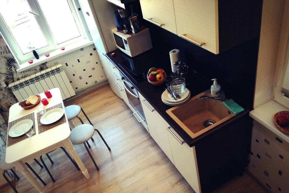 A compact kitchen with a sink, microwave, and dining area with chairs and a table set for two.