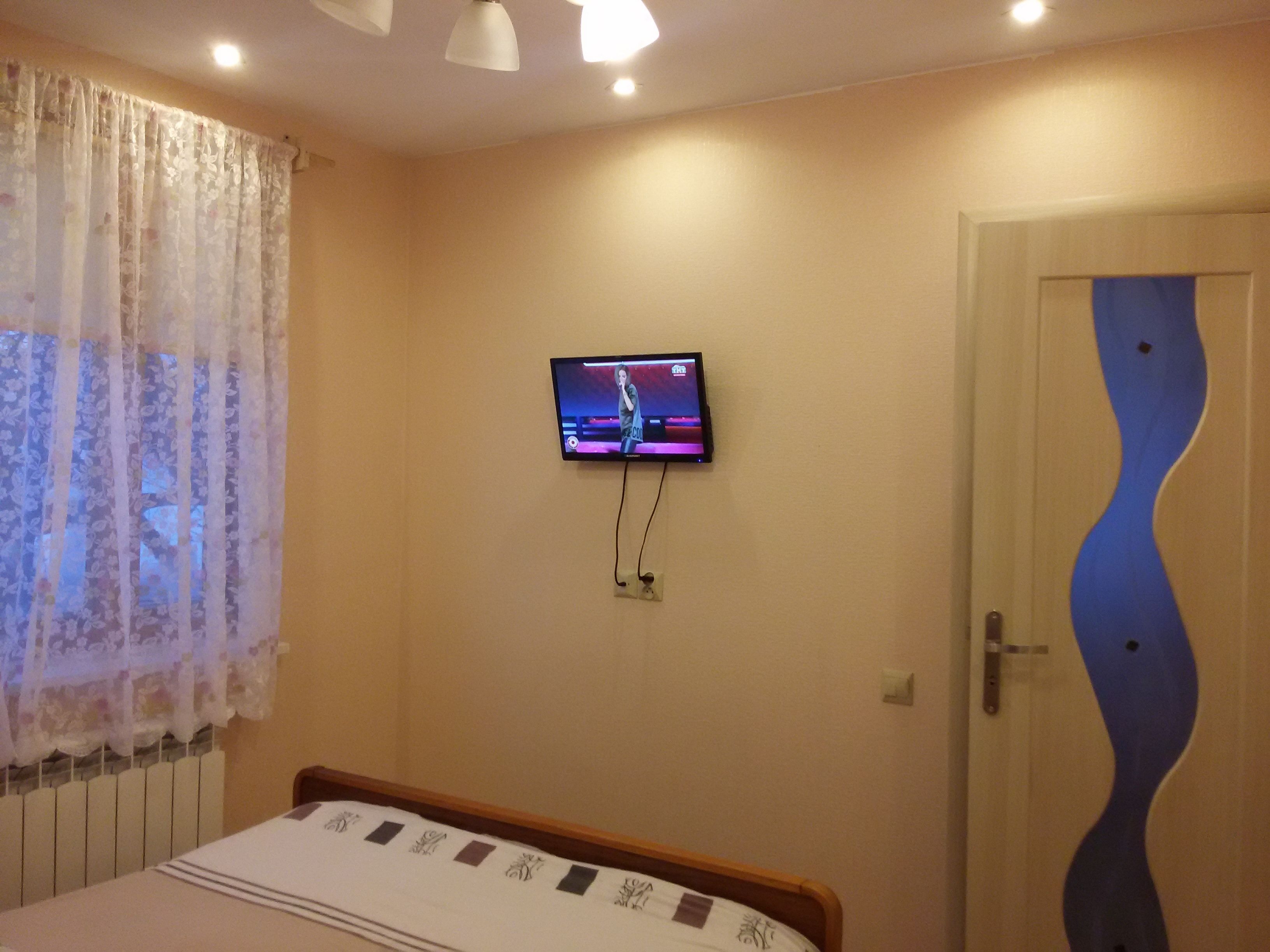 Ein Schlafzimmer mit einem Bett, einem an der Wand montierten Fernseher und einer Tür mit einem besonderen blauen Design.