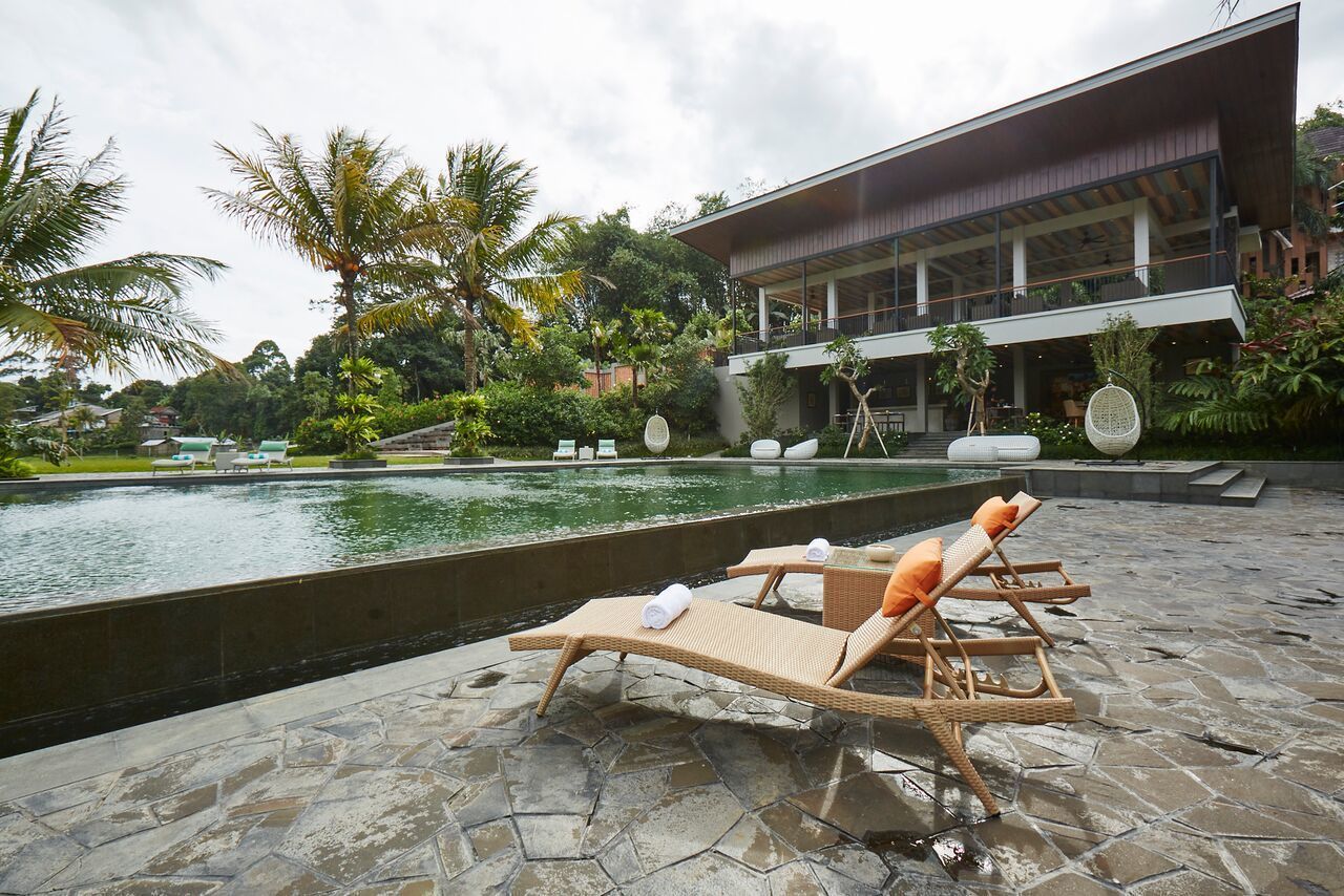 A poolside area with lounge chairs and a modern building in the background.