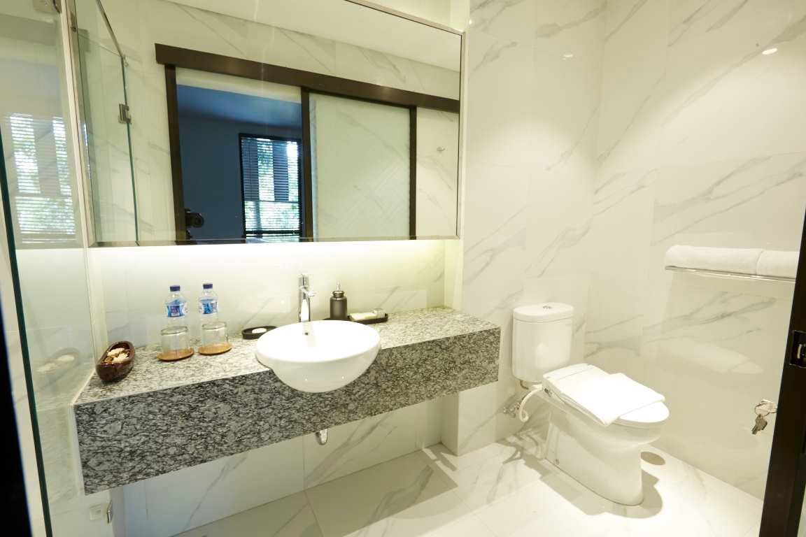 A modern bathroom with a granite countertop, white sink, and toilet.
