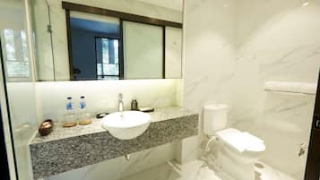 Un baño moderno con encimera de granito, lavamanos blanco e inodoro.