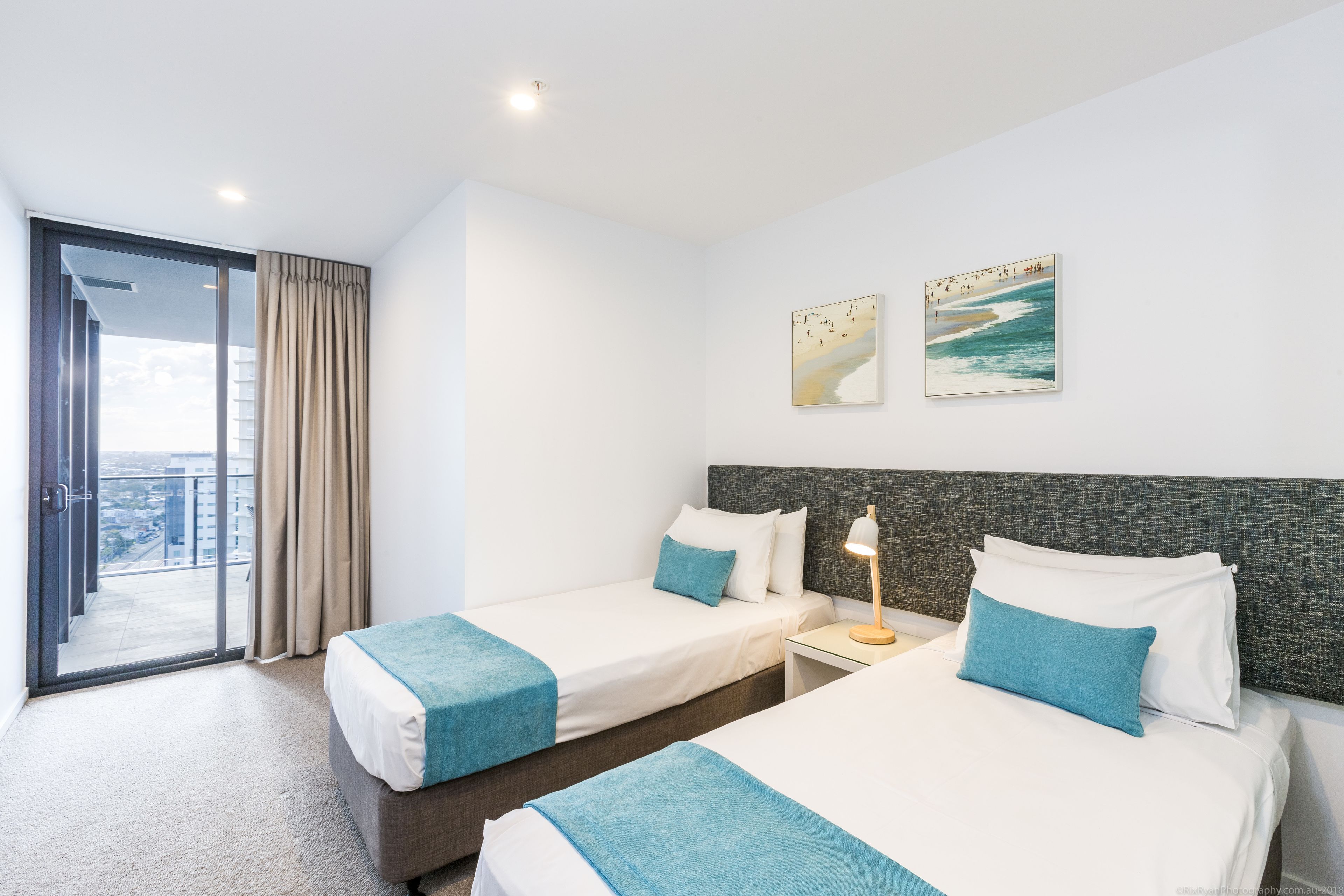 Une chambre d’hôtel avec deux lits, un balcon et une vue sur la ville.